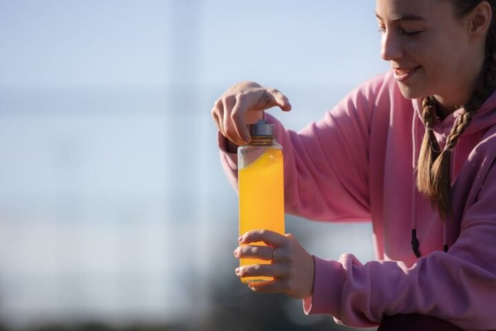 Woman opening bottle of orange sports drink